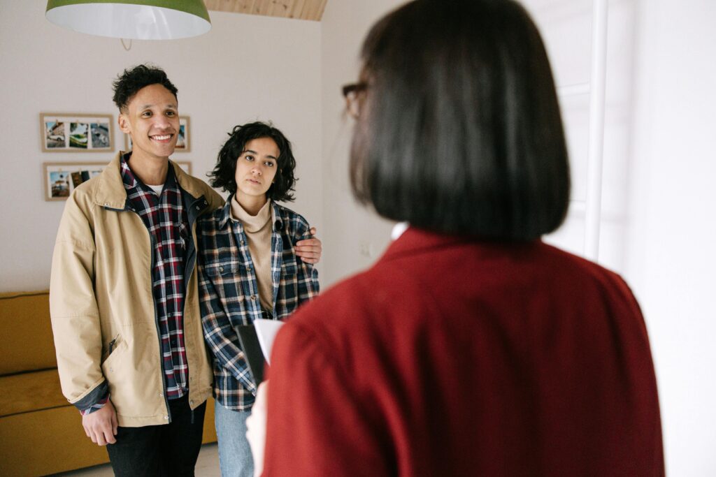 Young couple discussing real estate options with an agent indoors, highlighting home buying process.